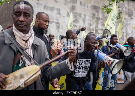 Parigi, Francia. 14 giugno 2024. I migranti cantano slogan sui megafoni durante la dimostrazione. Decine di persone hanno manifestato nei pressi di Place Trocadero a Parigi contro il razzismo e le politiche europee in materia di frontiere. Hanno anche chiesto la cancellazione della legge Darmanin e una revisione costituzionale del diritto di asilo a Mayotte. La protesta mirava anche a ricordare le vittime del tragico naufragio causato dalle autorità greche, che ha ucciso più di 600 persone al largo della costa greca di Pelo. (Foto di Telmo Pinto/SOPA Images/Sipa USA) credito: SIPA USA/Alamy Live News Foto Stock