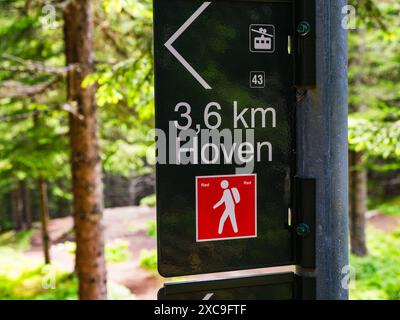 Un cartello segnaletico in Norvegia punta verso Hoven, che indica che si trova a 3,6 chilometri di distanza. Il cartello presenta anche un quadrato rosso con un'icona bianca o. Foto Stock