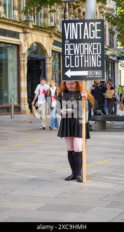 Cardiff, Galles 29 ottobre 2023: Grande segno tenuto da una persona attraente vestita con capelli lunghi. La Hayes pubblicizza abiti vintage e rilavorati Foto Stock