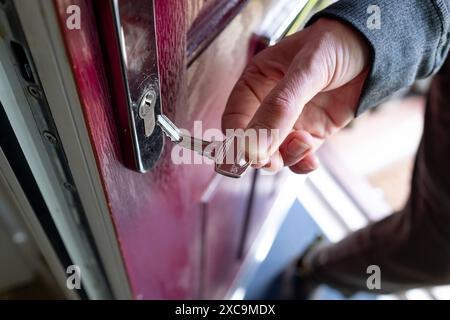 Una chiave piegata tenuta in mano accanto alla serratura di una portiera anteriore dopo essere stata piegata nella serratura. Foto Stock