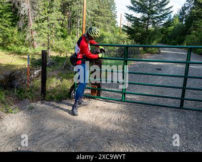 WA25385-00...WASHINGTON - ciclista che sblocca una delle tante porte sul percorso Palouse-Cascades State Park Foto Stock