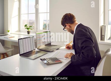 Contabile maschile che lavora con il rapporto finanziario in ufficio Foto Stock