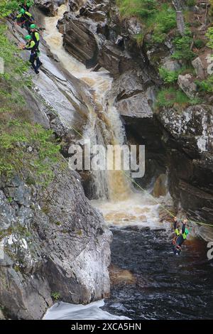 Gente che cala giù per la faccia rocciosa e in una piscina sotto le Cascate di Bruar. Le cascate di Bruar sono una serie di cascate sull'acqua di Bruar in Scozia. Foto Stock