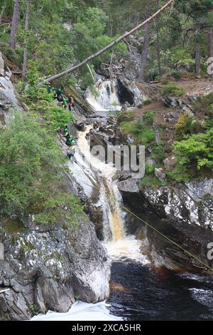 Gente che cala giù per la faccia rocciosa e in una piscina sotto le Cascate di Bruar. Le cascate di Bruar sono una serie di cascate sull'acqua di Bruar in Scozia. Foto Stock