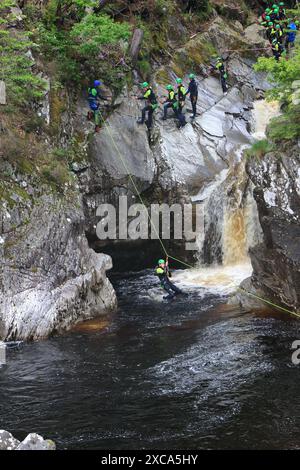 Gente che cala giù per la faccia rocciosa e in una piscina sotto le Cascate di Bruar. Le cascate di Bruar sono una serie di cascate sull'acqua di Bruar in Scozia. Foto Stock