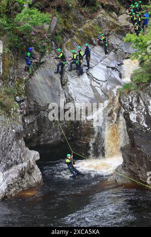 Gente che cala giù per la faccia rocciosa e in una piscina sotto le Cascate di Bruar. Le cascate di Bruar sono una serie di cascate sull'acqua di Bruar in Scozia. Foto Stock