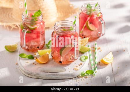 Limonata gustosa e dolce con frutta in vaso e ghiaccio tritato. Bevanda ghiacciata in un recipiente. Foto Stock