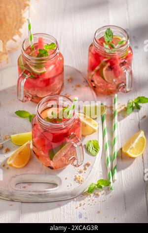 Limonata sana e gustosa con frutta in vaso e ghiaccio tritato. Bevanda ghiacciata in un recipiente. Foto Stock