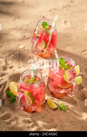 Limonata fredda e gustosa con frutta in vaso e ghiaccio tritato. Bevanda ghiacciata in un recipiente. Foto Stock