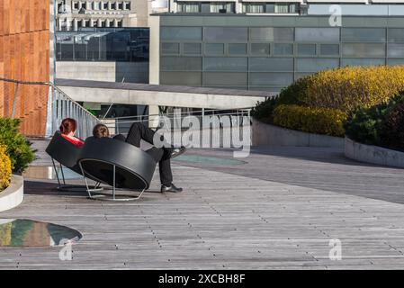 Coppia seduta su poltrone sulla terrazza Urban Outdoor con tavole di legno Foto Stock