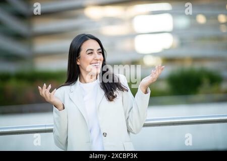 Donna in White Blazer che sorride all'aperto in un ambiente urbano Foto Stock