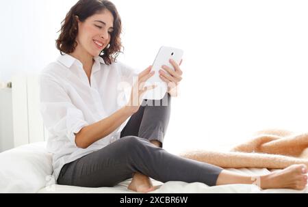 Donna che utilizza computer tablet e sorridente Foto Stock