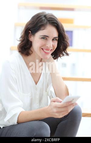 Donna seduta su scale e utilizzo di smart phone Foto Stock