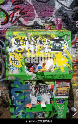 Londra, Regno Unito. Cestino pesantemente graffitizzato e difficilmente riconoscibile sul sentiero del Regents Canal a Camden Lock, vicino a un muro di graffiti Foto Stock