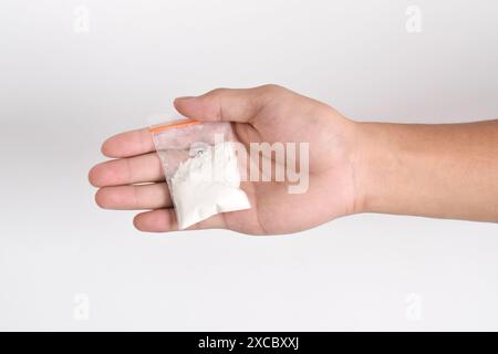 La mano fornisce cocaina in un contenitore di plastica isolato su sfondo bianco. Illustrazione di sostanze stupefacenti illegali, narcotici Foto Stock