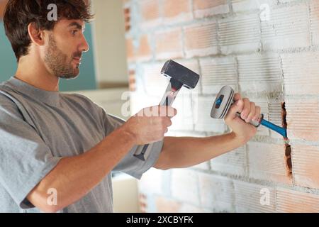 Strato di mattoni che crea una scanalatura nella parete di mattoni per posizionare i fili elettrici. Attrezzi manuali per martello e scalpello. Costruzione. Lavori di costruzione. Donostia. San Sebas Foto Stock