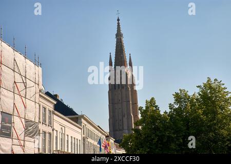 Bruges, Belgio; giugno 06.2024; la torre della chiesa di nostra Signora in stile gotico con vecchie case con frontoni a punta al sole come parte dell'UNESCO W Foto Stock