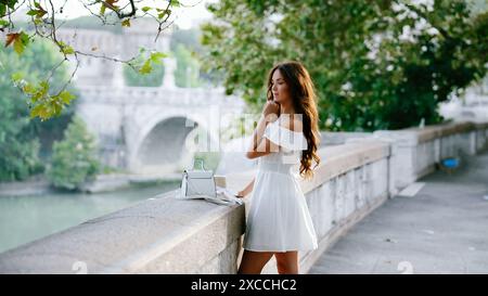 Roma, Italia. Ragazza in bianco posa sullo sfondo di un ponte sotto un bellissimo albero Foto Stock