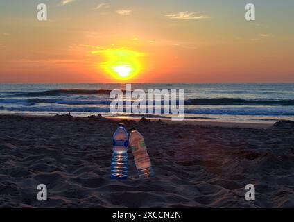 Due bottiglie di plastica su una spiaggia al tramonto Foto Stock