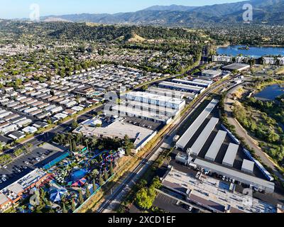 Vista aerea di un quartiere periferico con un parco acquatico, edifici industriali e un lago sullo sfondo in una giornata di sole Foto Stock