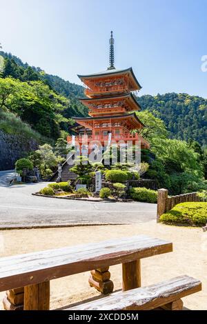 Nachi-Katsuura, Giappone -05.09.2024: La pagoda rossa a tre piani del Tempio buddista Seigantoji di fronte alle Cascate di Nachi. Splendido paesaggio naturale a Nach Foto Stock