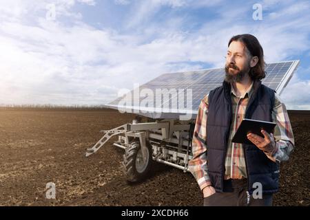 L'agricoltore controlla macchine agricole autonome alimentate da energia solare. Foto Stock