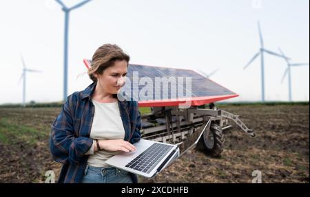 L'agricoltore controlla macchine agricole autonome alimentate da energia solare. Foto Stock