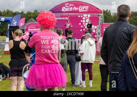 Warrington, Cheshire, Regno Unito. 16 giugno 2024. La "Race for Life" annuale a sostegno della Cancer Research UK si è svolta a Victoria Park, Warrington. Il tema è indossare il rosa e raccogliere fondi per la ricerca sul cancro. I volontari hanno aiutato la causa vestendo e vendendo merchandise Credit: John Hopkins/Alamy Live News Foto Stock