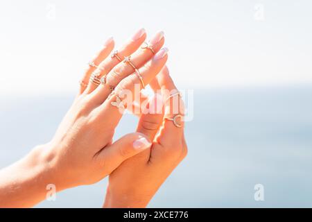 Una donna tiene le mani in alto con una varietà di anelli sulle dita. Gli anelli sono di diverse dimensioni e stili, e sono tutti posizionati su di lei Foto Stock