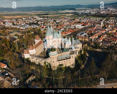 Vista panoramica aerea di Bojnicky Zamok e dei tetti rossi degli edifici della città di Bojnice, Slovacchia. Alto castello sulla collina e sul parco, palazzo dei re con elementi gotici e rinascimentali Foto Stock