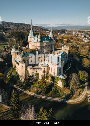 Vista aerea dall'alto di Bojnicky Zamok, viaggio in Slovacchia. Al di sopra della scena ad alto angolo di famosi edifici e parco nel Castello di Bojnice, paesaggio serale con lunghe ombre di alberi e fortezza medievale Foto Stock