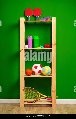 Ripiani con diverse attrezzature sportive contro il muro verde Foto Stock