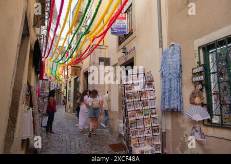 Persone che camminano in una stretta strada del quartiere di Alfama a Lisbona, in Portogallo, durante le popolari feste dei Santi Foto Stock