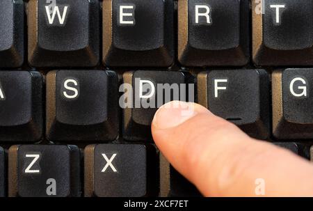 Uomo che preme un singolo tasto D su una moderna tastiera di un computer portatile, spinge un dito verso l'alto un tasto della vista dall'alto, una persona. Simbolo di una sola lettera Foto Stock