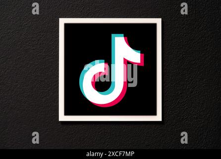 Logo dell'app ByteDance TikTok cartellino quadrato appeso su una parete scura, vista frontale, primo piano, nessuno. Tik Tok tendenze segnaletica di zona, logo dell'azienda del marchio nota Foto Stock