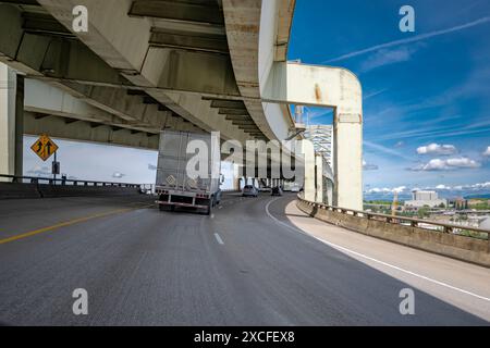 Trattore semi-motrice blu con carro di perforazione di grandi dimensioni che trasporta merci commerciali in semirimorchio frigorifero che viaggia su strada con due ruote Foto Stock