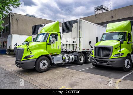 Trattore semi-camion con carro di perforazione di grandi dimensioni verde con cabina corta e semirimorchi con frigorifero per carichi locali in piedi nel porto di carico del magazzino Foto Stock