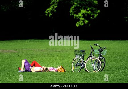 Due donne stese sull'erba nel Giardino inglese, Monaco di Baviera, Germania Foto Stock