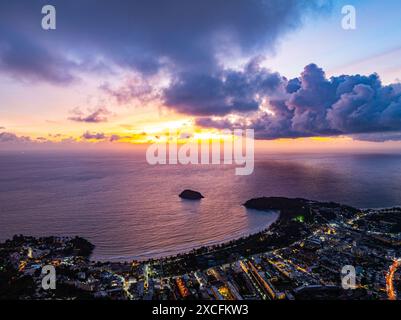 Vista aerea le nuvole oscurano lo splendido cielo mentre il sole tramonta. Le luci lungo la spiaggia iniziano ad accendersi quando il crepuscolo si avvicina. Ci sono molti edifici, Foto Stock