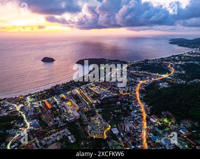 Vista aerea le nuvole oscurano lo splendido cielo mentre il sole tramonta. Le luci lungo la spiaggia iniziano ad accendersi quando il crepuscolo si avvicina. Ci sono molti edifici, Foto Stock