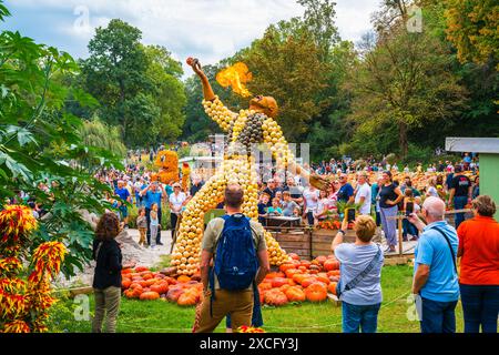 Ludwigsburg, Germania, 3 ottobre 2023, giardini barocchi in fiore visitati dai turisti che osservano la scultura della zucca, la respirazione del fuoco che sputa il fuoco Foto Stock