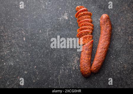 Salsiccia affumicata affumicata a fette sul tavolo nero. Vista dall'alto. Foto Stock