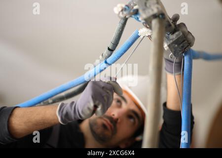 Elettricista che ripara l'impianto elettrico in una casa in fase di riforma Foto Stock