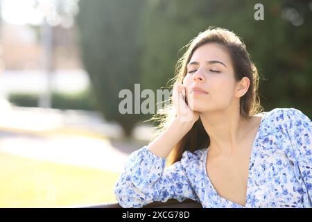 Donna che si rilassa seduta su una panchina in un parco da sola Foto Stock