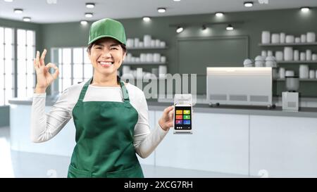 I venditori asiatici indossano grembiule verde e berretto verde sorridenti con lettore di carte di trasporto a mano nel negozio di caffè Foto Stock