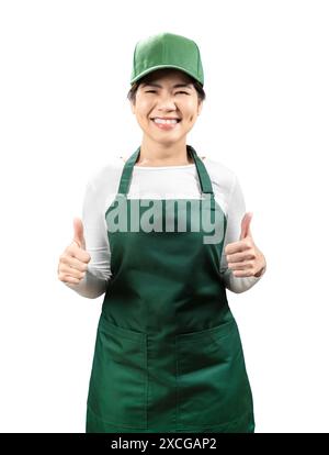 I venditori asiatici indossano grembiule verde e berretto verde sorridenti e pollice isolato sul bianco Foto Stock
