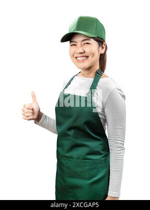 I venditori asiatici indossano grembiule verde e berretto verde sorridenti e pollice isolato sul bianco Foto Stock