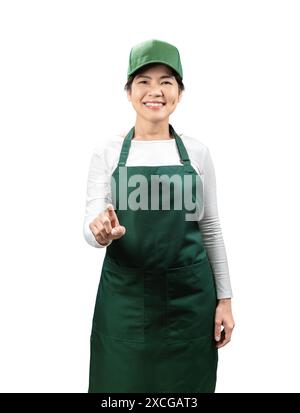 I venditori asiatici indossano grembiule verde e berretto verde sorridenti con punta del dito isolata su bianco Foto Stock