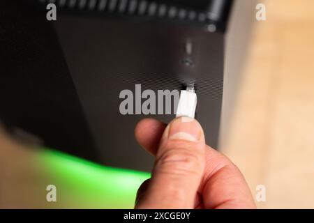 Uomo d'affari che inserisce l'unità flash USB bianca a un computer nero in primo piano Foto Stock