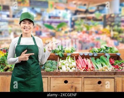 I venditori asiatici indossano grembiule verde e berretto verde sorridenti sul mercato Foto Stock